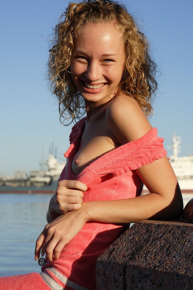 12P Curly haired girl exposes her pussy and small tits while hanging out on a pier