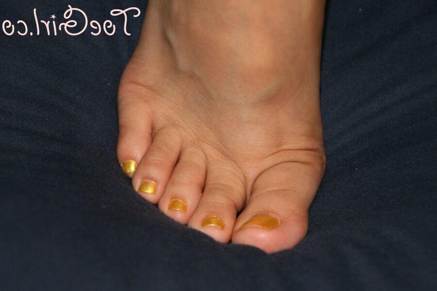 16P Mujer caucásica muestra las uñas de sus pies pintadas mientras usa sandalias
