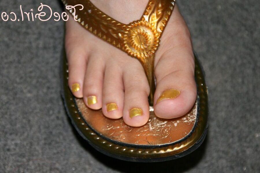 16P Mujer caucásica muestra las uñas de sus pies pintadas mientras usa sandalias