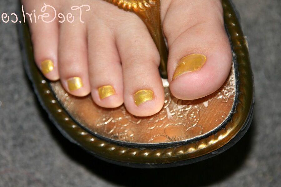 16P Mujer caucásica muestra las uñas de sus pies pintadas mientras usa sandalias