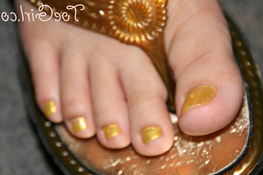 16P Mujer caucásica muestra las uñas de sus pies pintadas mientras usa sandalias
