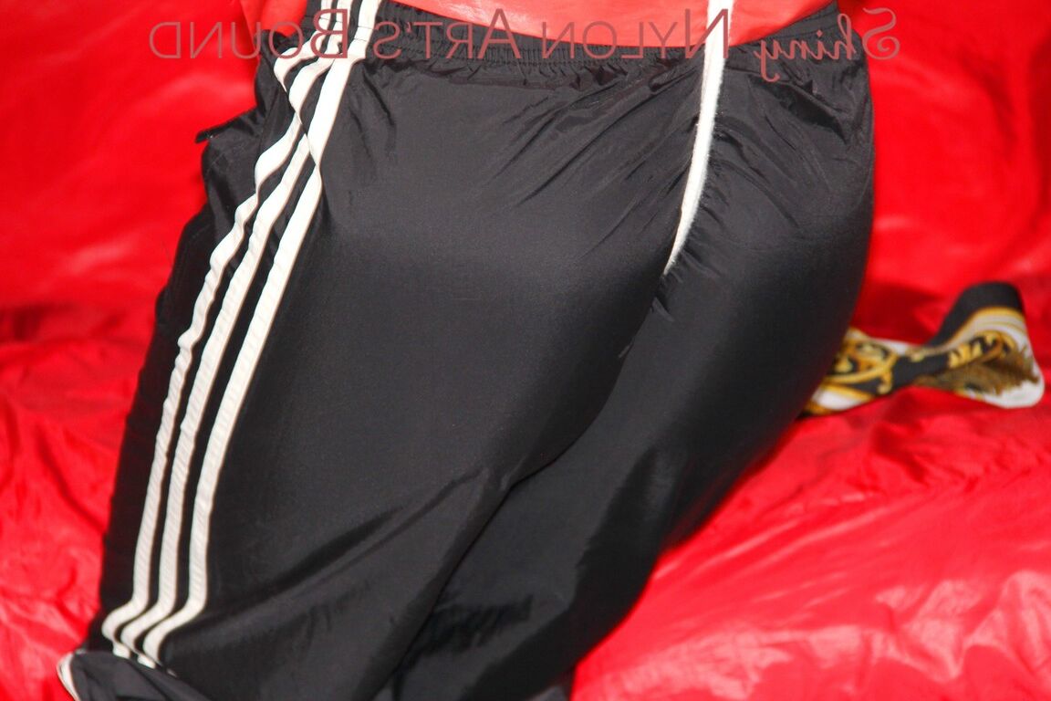 16P Sonja trägt eine schwarze Regenhose und eine rote Regenjacke aus glänzendem Nylon