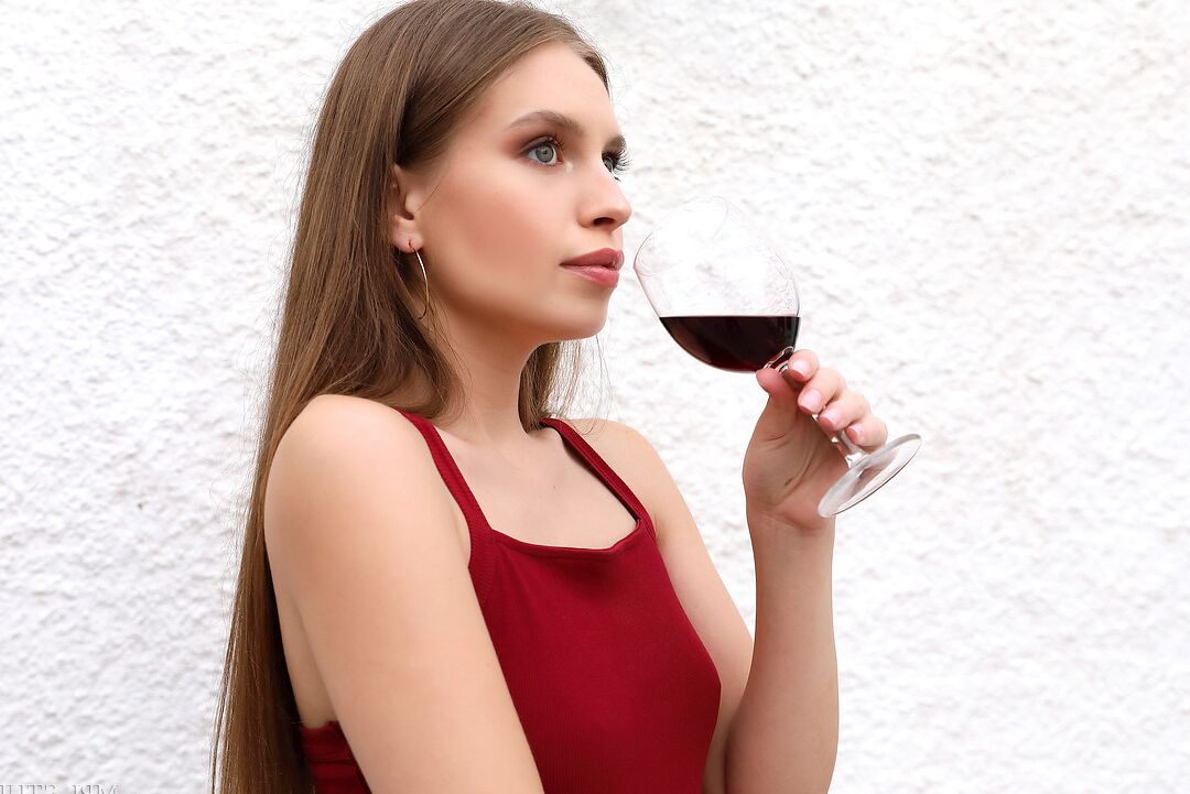 12P Beautiful girl removes a red dress over a glass of wine to pose in the nude