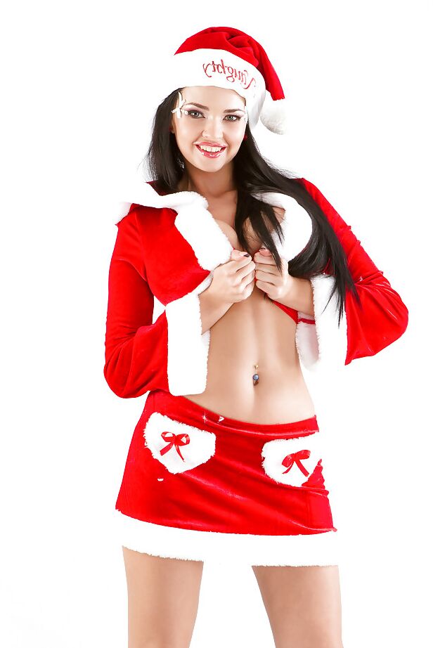 Sha Rizel, mannequin européen aux gros seins, pose en costume de Père Noël sexy et talons hauts.