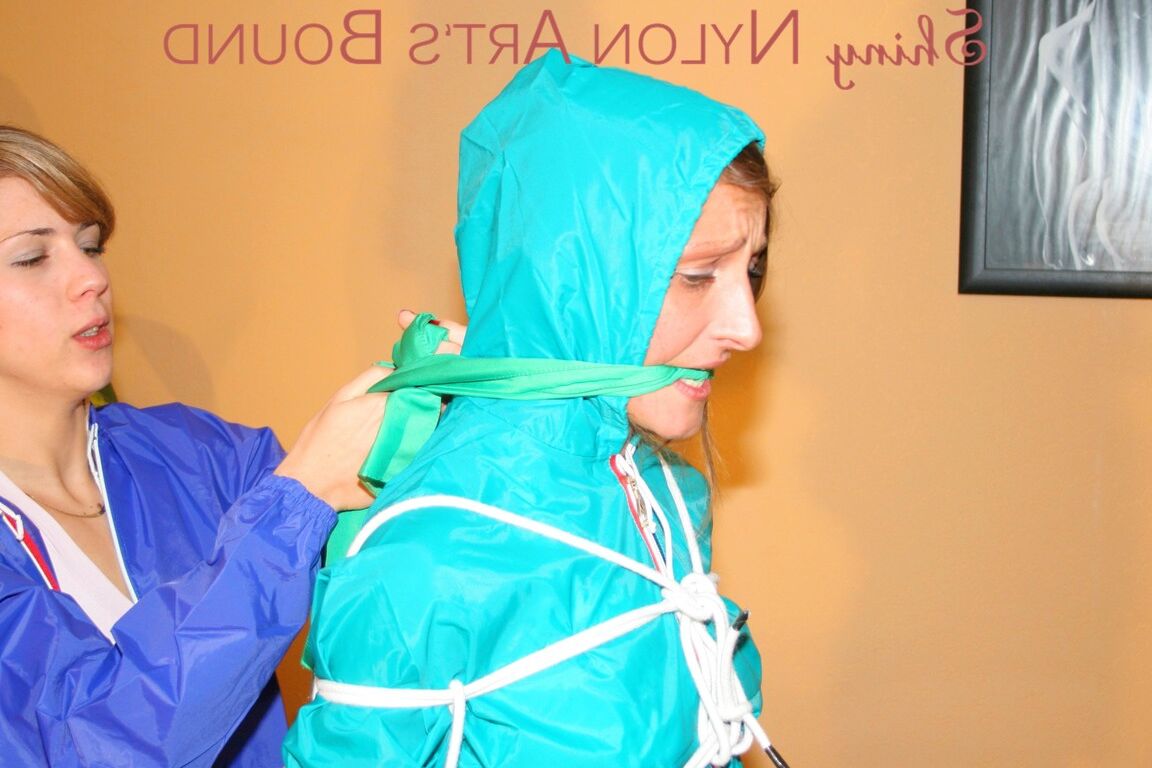 16P Leonie amarra e amordaça Stella usando capa de chuva sexy e brilhante de náilon Fotos