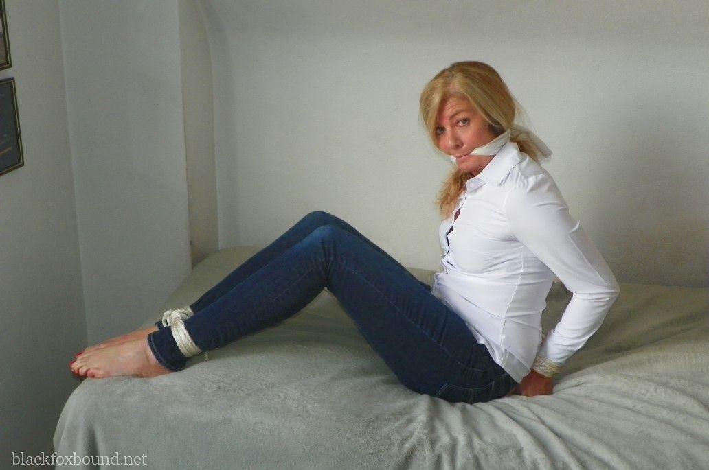 16P Mulher loira com decote amordaçado e amarrado em uma blusa branca e jeans azul