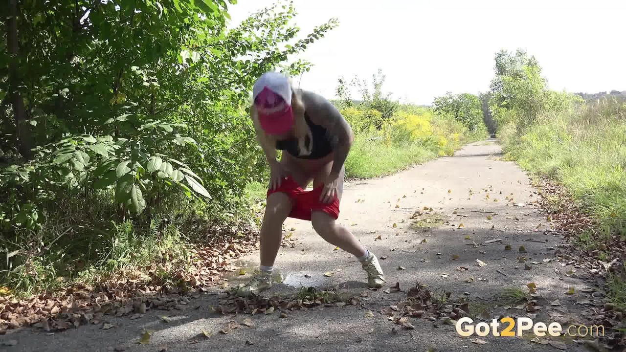 15P Vollbusige blonde Joggerin hockt mit heruntergelassenen Shorts auf der Laufstrecke, um zu pinkeln