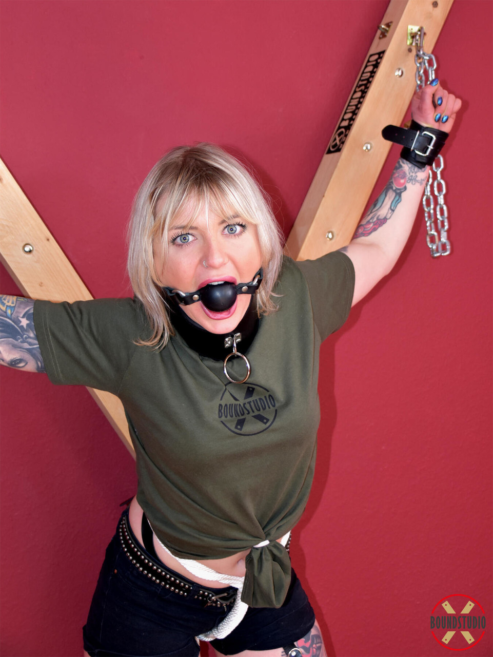 16P Blonde chick Roxxxi Manson is ball gagged while chained to a St Andrews cross
