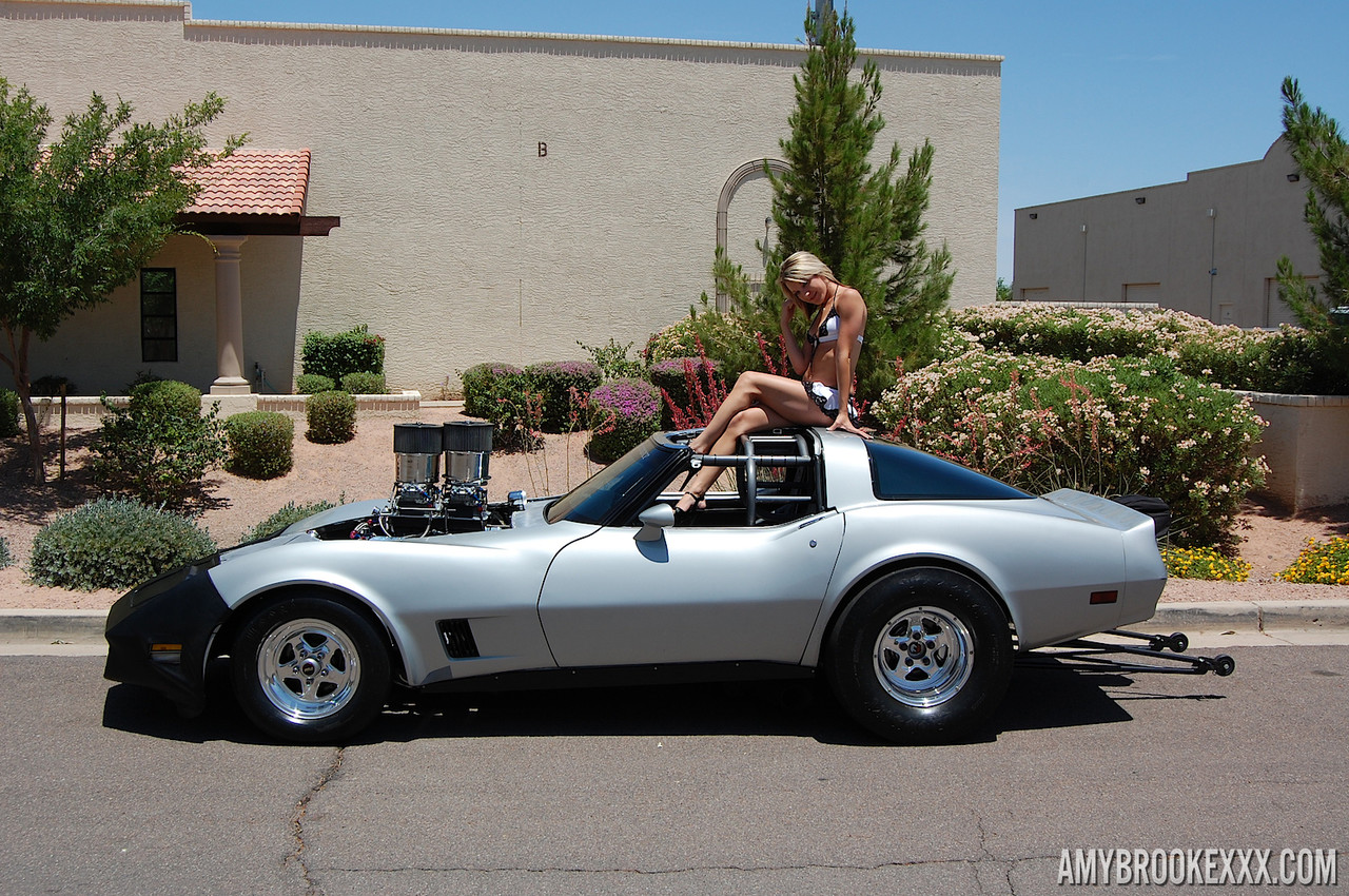 Amy Brooke, mannequin solo de 15P, expose son string sous sa jupe au sommet d'une voiture de sport.
