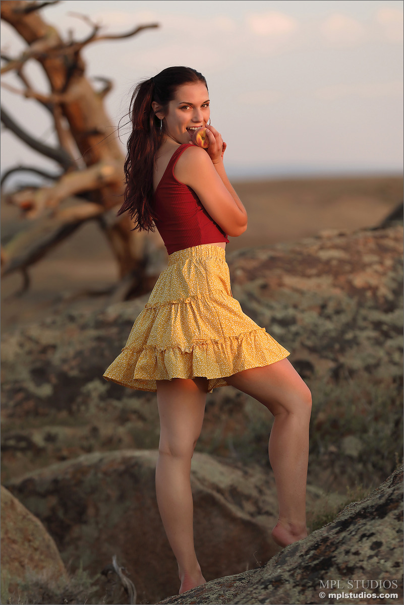 A modelo 12P Glamour solta o cabelo preso em um rabo de cavalo enquanto está nua no topo de uma colina rochosa