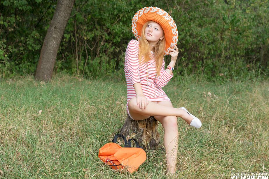 20P Young girl with red hair holds an orange while posing naked on a blanket