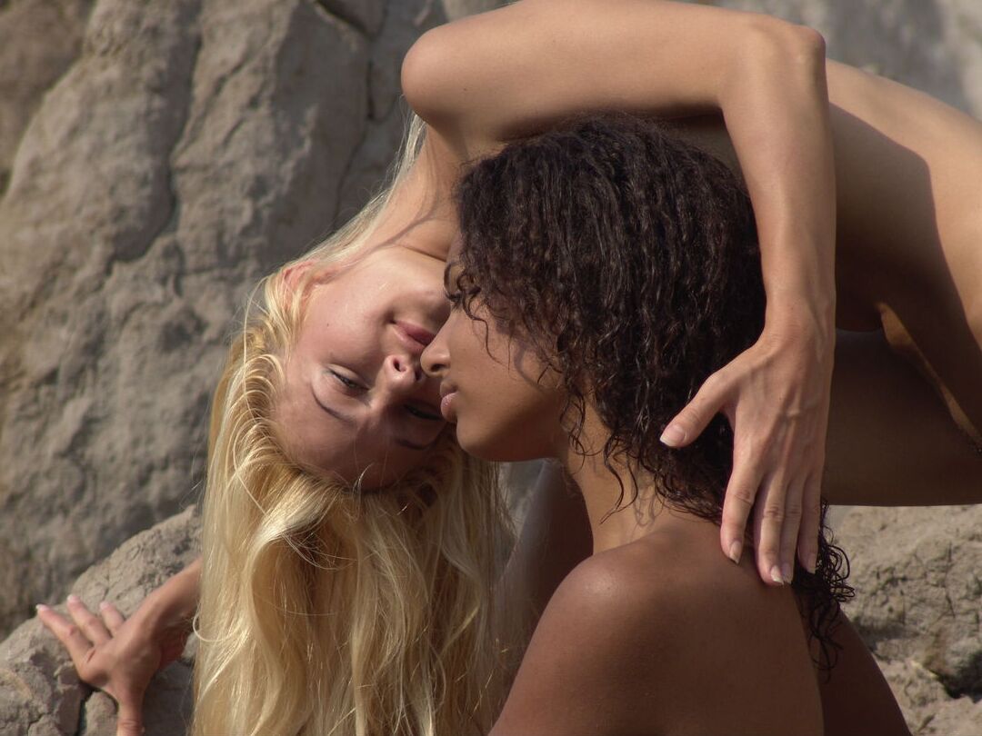16P Garotas negras e brancas exibem suas bundas nuas enquanto posam nuas contra uma rocha