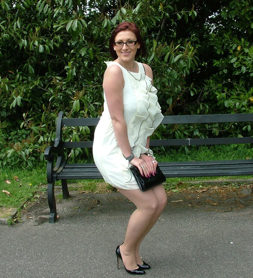 16P Thick woman in glasses shows off her stiletto heels on a park bench