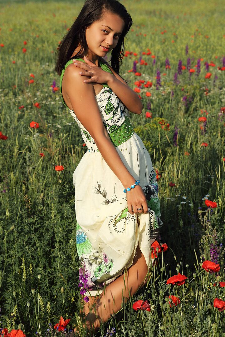 12P Chica solitaria de cabello oscuro se quita el vestido para modelar desnuda entre flores silvestres