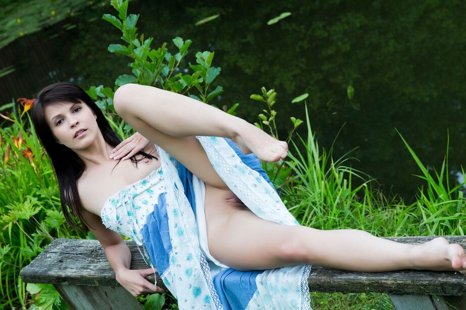 16P A adolescente de cabelos escuros Zelda levanta um vestido longo para expor sua bela buceta na água