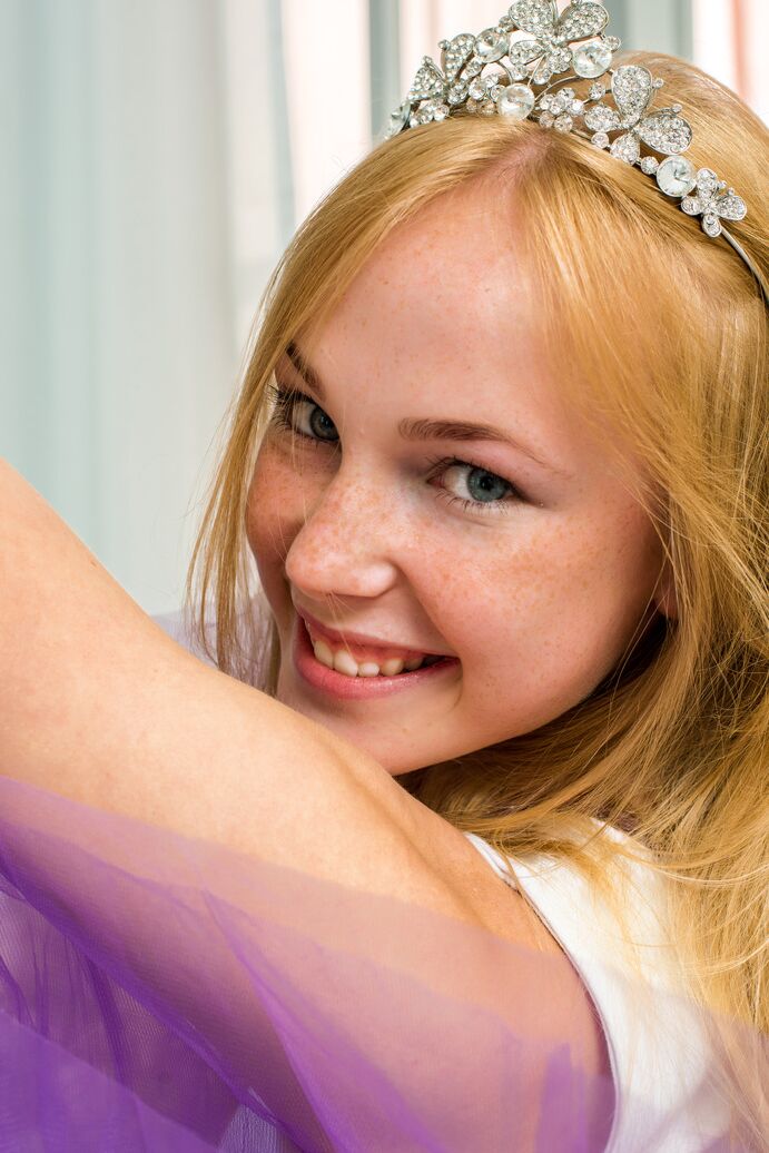 20P Das jung aussehende Mädchen Runa trägt eine Tiara, während sie sich auf spielerische Weise auszieht