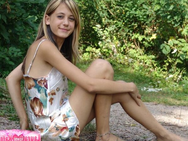 15P Jovencita de aspecto inocente se desnuda sobre un fondo de follaje verde