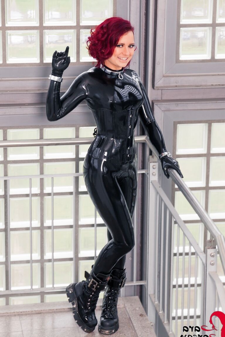 12P Lara Larsen, rousse à collier et vêtue de latex, enfile un bâillon-boule en action solo