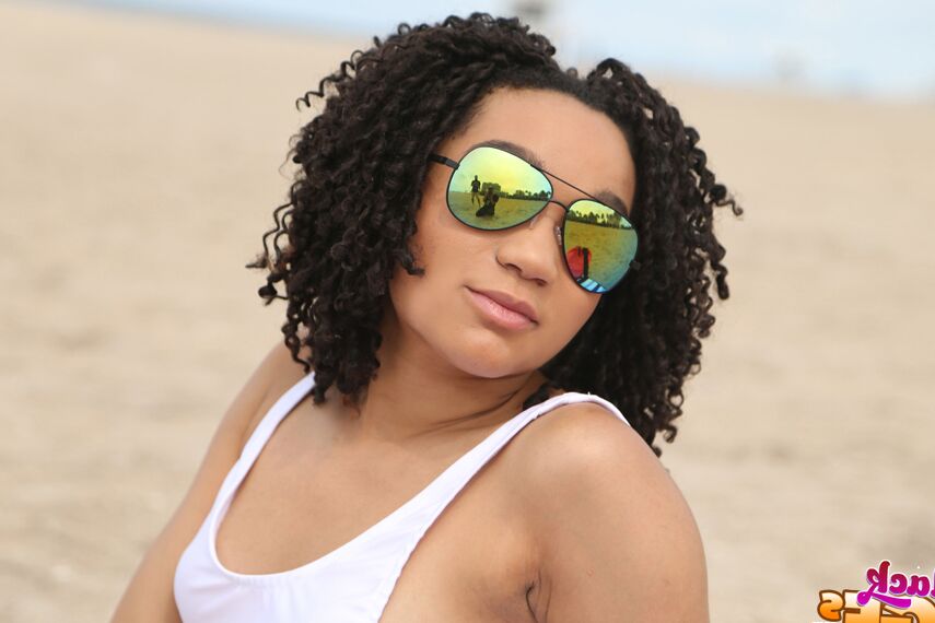 Pixie, amateur ébène 16P, pose sur la plage dans sa jolie lingerie.