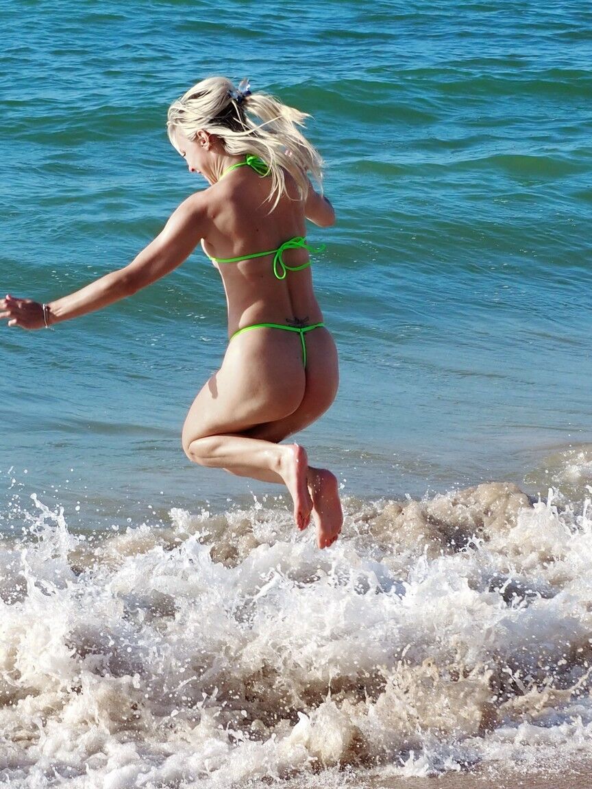 12P Blonde teen Chloe Toy steps into the ocean surf wearing a skimpy bikini
