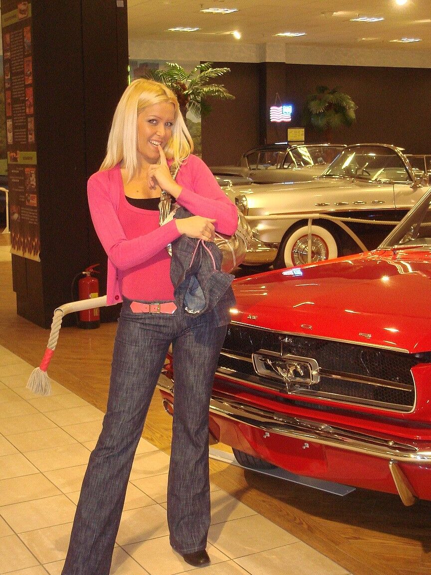 17P Sophie Moone, une MILF blonde hongroise, pose entièrement habillée devant des voitures.