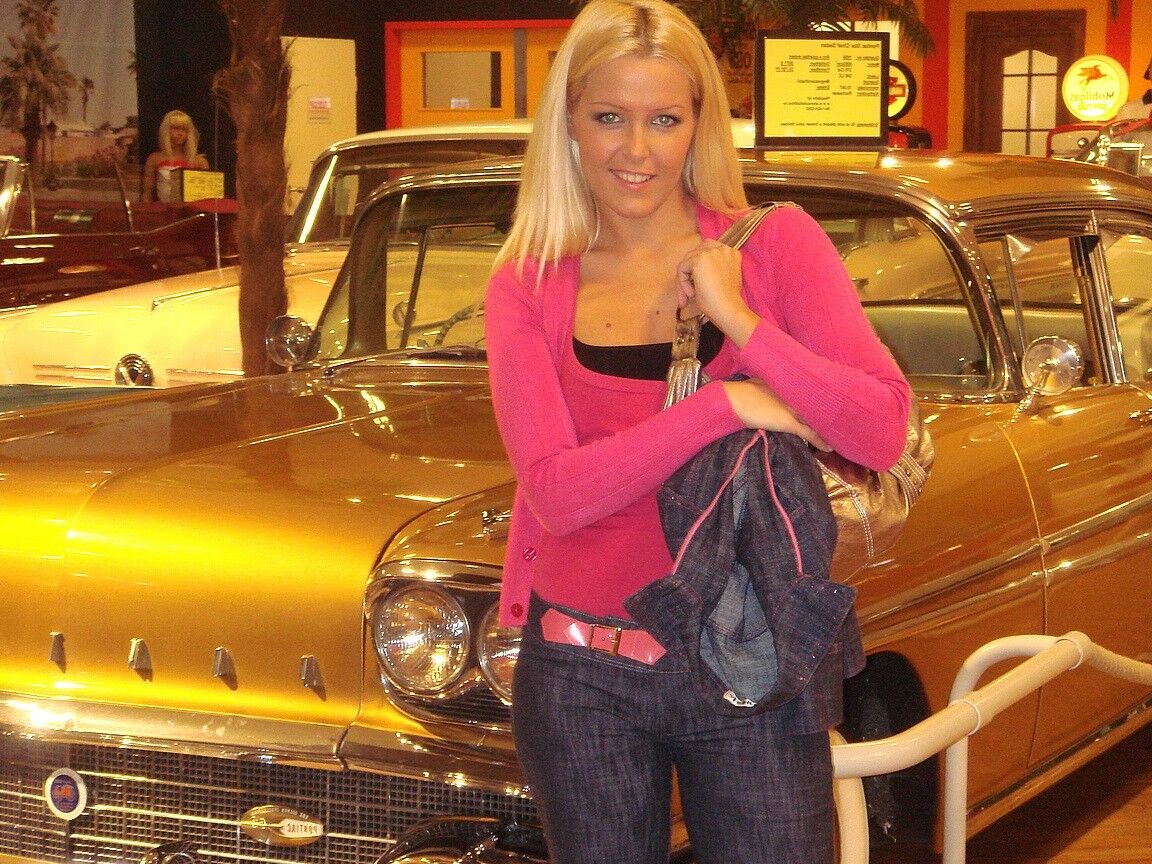 17P Sophie Moone, une MILF blonde hongroise, pose entièrement habillée devant des voitures.