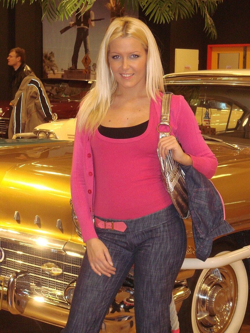 17P Sophie Moone, une MILF blonde hongroise, pose entièrement habillée devant des voitures.