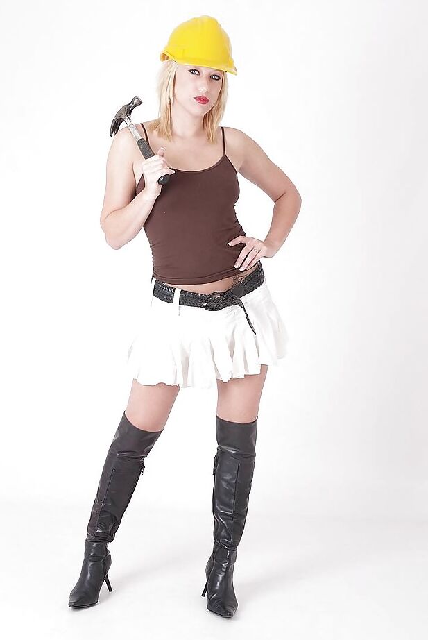 16P La blonde Axa pose avec des bottes en cuir et un casque tout en exhibant ses seins.
