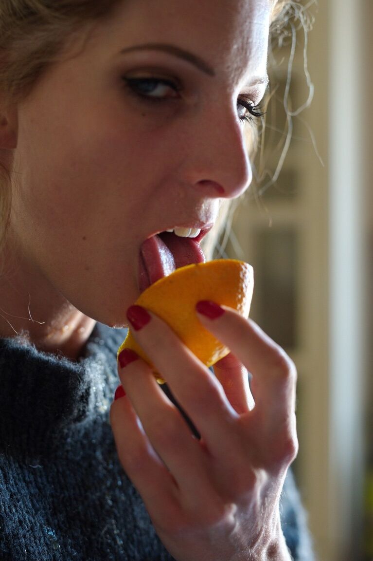 12P Tall blonde Rebecca Leah consumes an orange while freeing tits from a sweater
