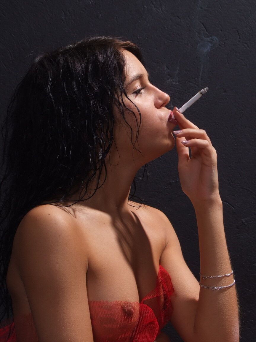 16P Une adolescente aux cheveux noirs révèle son corps nu en fumant une cigarette