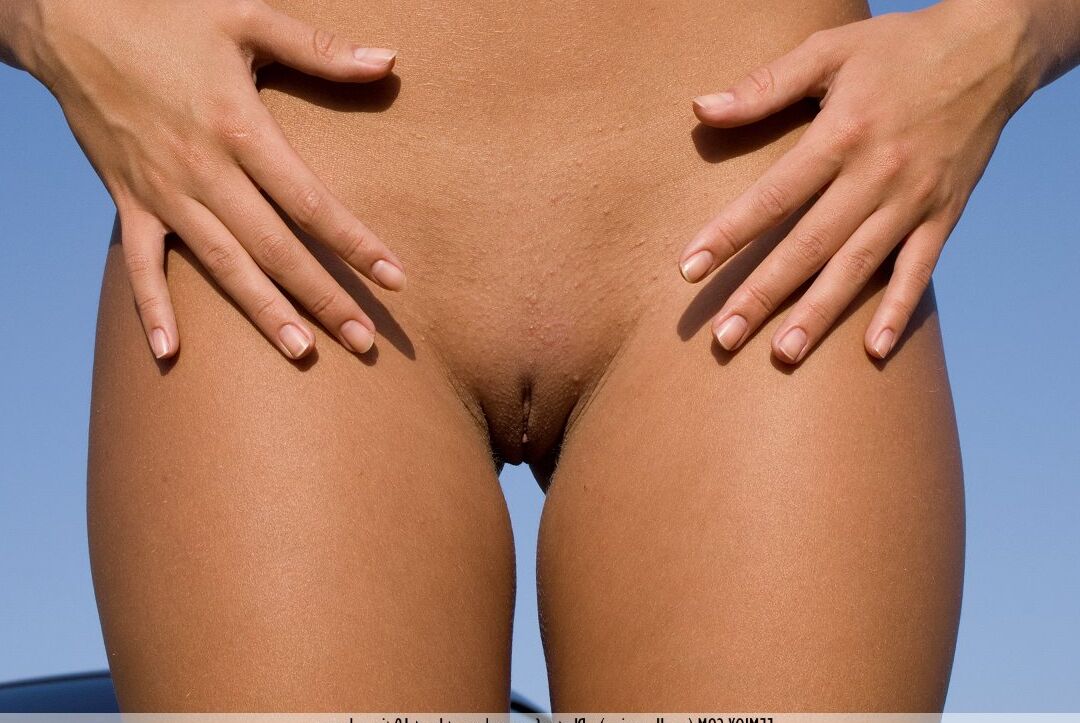 16P Anju, blonde naturelle, prend de superbes poses nues sur le capot d'une voiture à l'extérieur.