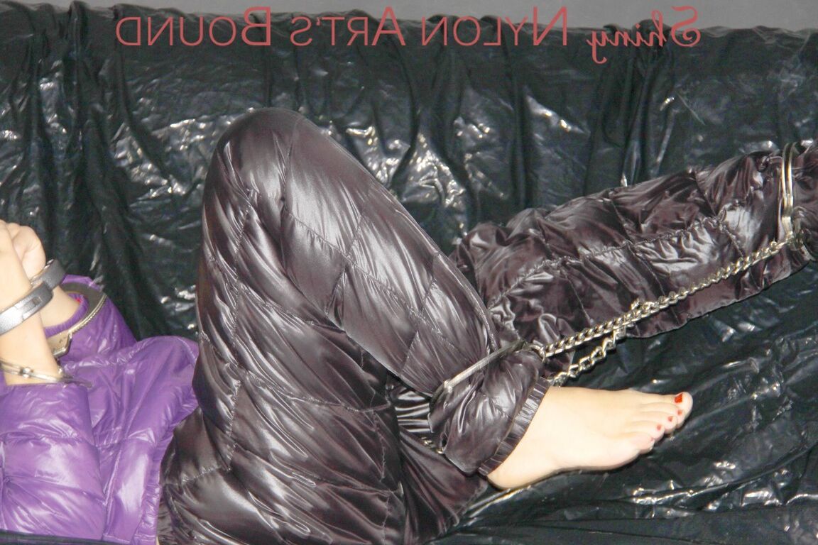 16P Sandra ist mit Handschellen und einem Pranger in heißem Lila auf einem Sofa gefesselt und geknebelt