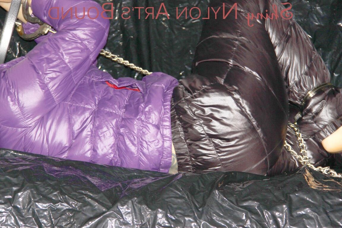 16P Sandra ist mit Handschellen und einem Pranger in heißem Lila auf einem Sofa gefesselt und geknebelt