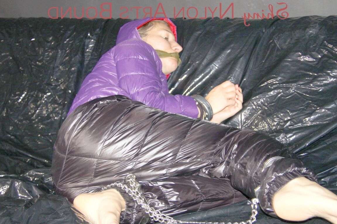 16P Sandra ist mit Handschellen und einem Pranger in heißem Lila auf einem Sofa gefesselt und geknebelt