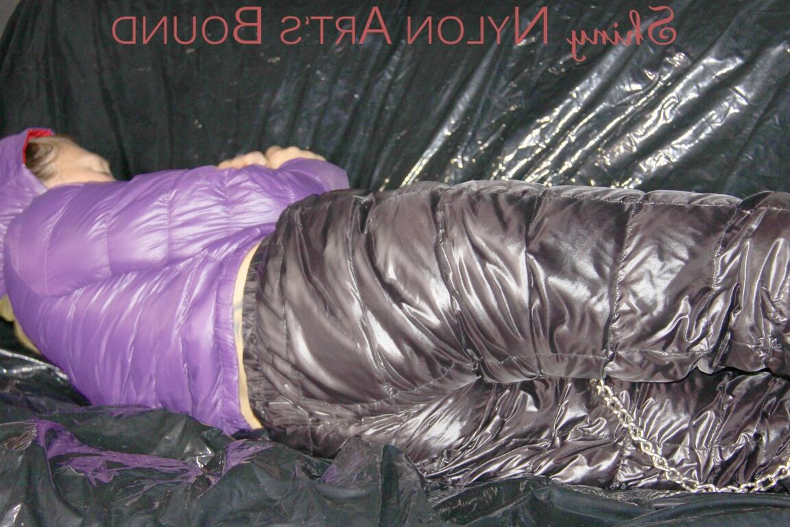 16P Sandra ist mit Handschellen und einem Pranger in heißem Lila auf einem Sofa gefesselt und geknebelt