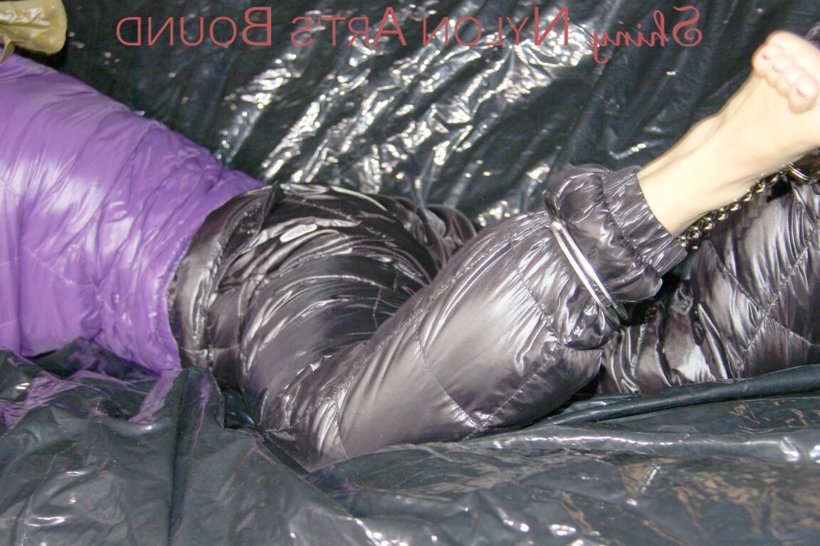 16P Sandra ist mit Handschellen und einem Pranger in heißem Lila auf einem Sofa gefesselt und geknebelt
