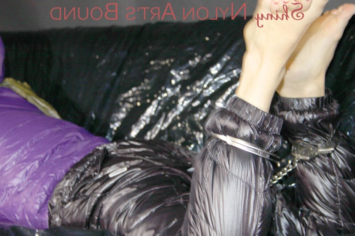 16P Sandra ist mit Handschellen und einem Pranger in heißem Lila auf einem Sofa gefesselt und geknebelt