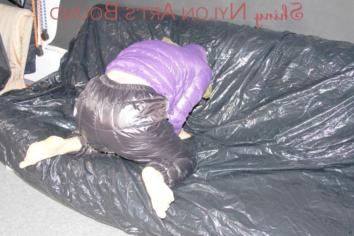 16P Sandra ist mit Handschellen und einem Pranger in heißem Lila auf einem Sofa gefesselt und geknebelt