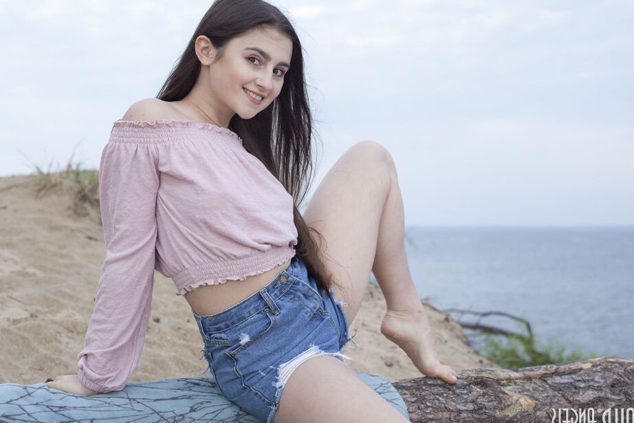 20P Young brunette Sara highlights her hairless pussy while naked on a beach