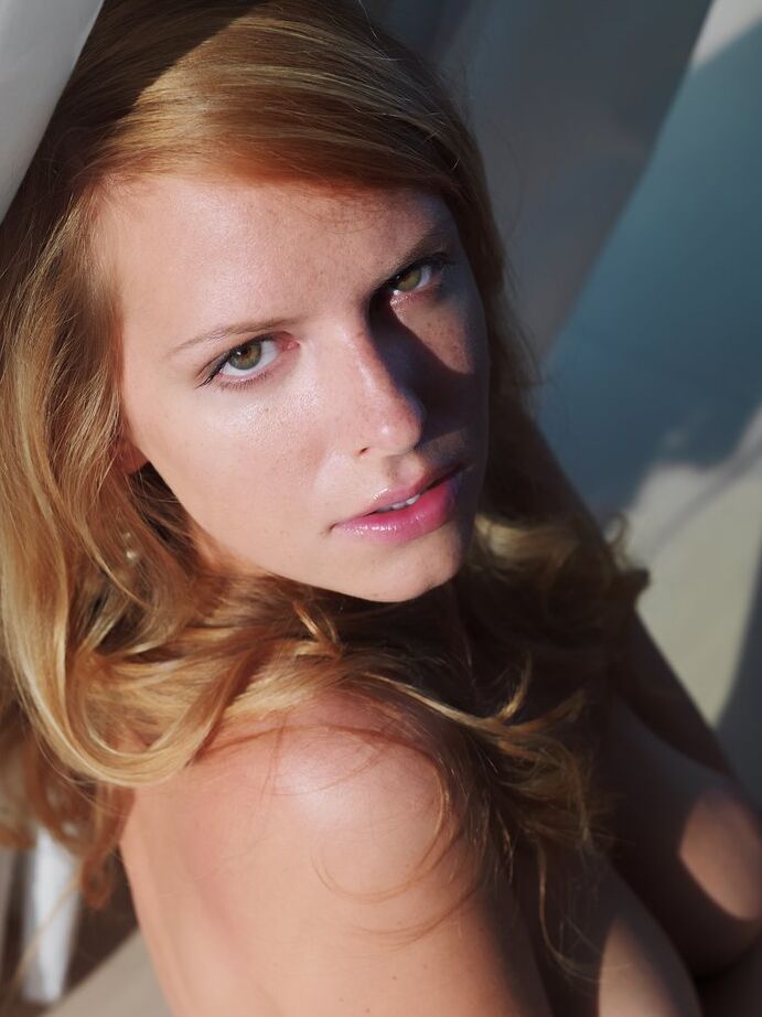 16P Beautiful redhead Tubbea gets naked in high heels near a window