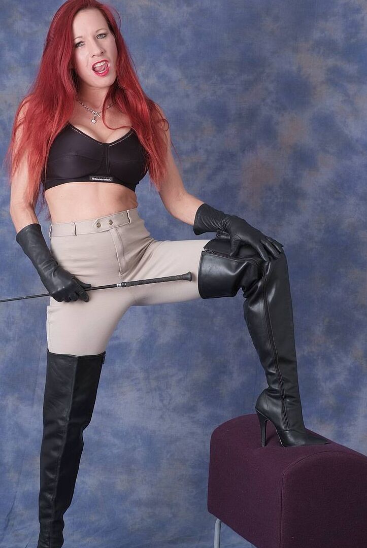 15P Dominant redhead Faye bares her fake tits while flexing a whip in leather wear