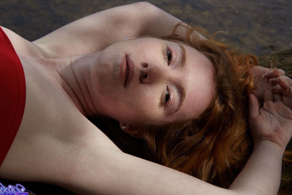15P Young redhead Nicki Blue bare her small tits while standing in a stream