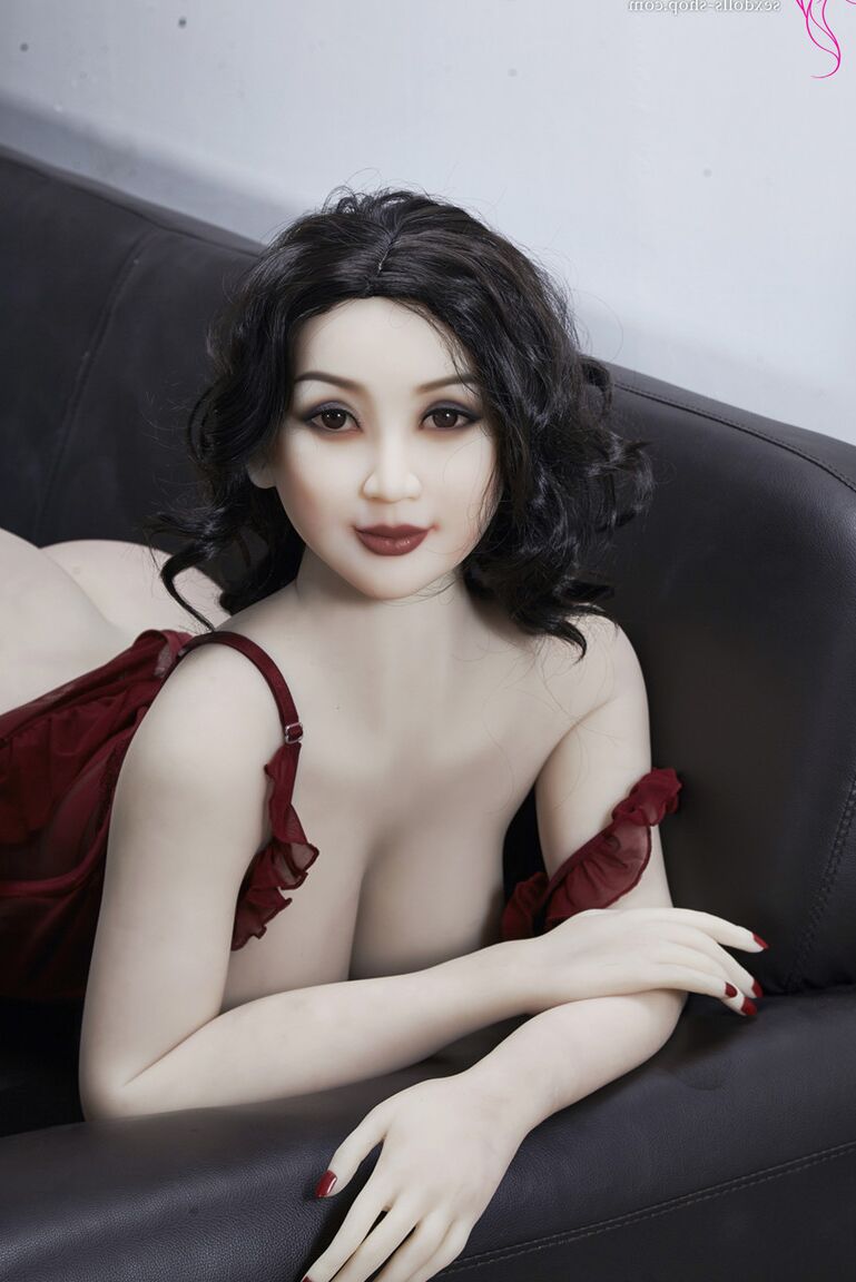 21P La muñeca sexual de pelo oscuro Xiu hace alarde de sus grandes tetas y su gran culo en un sofá negro