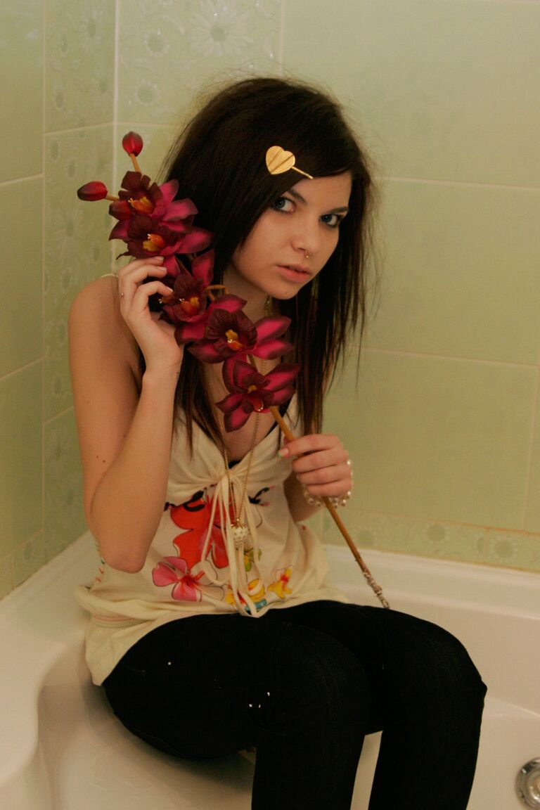 15P Cute girl Kaira 18 holds a stalk of flowers while posing clothed in a bathroom