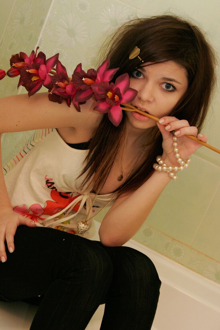 15P Cute girl Kaira 18 holds a stalk of flowers while posing clothed in a bathroom