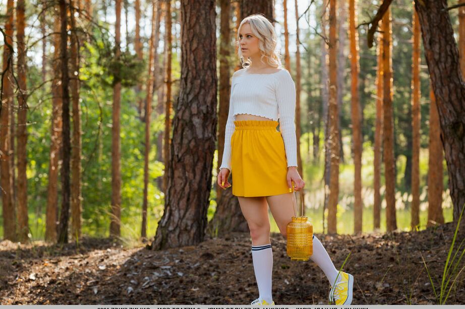 18P Nikki Hill bends over on the picnic mat in the middle of the forest, puts down