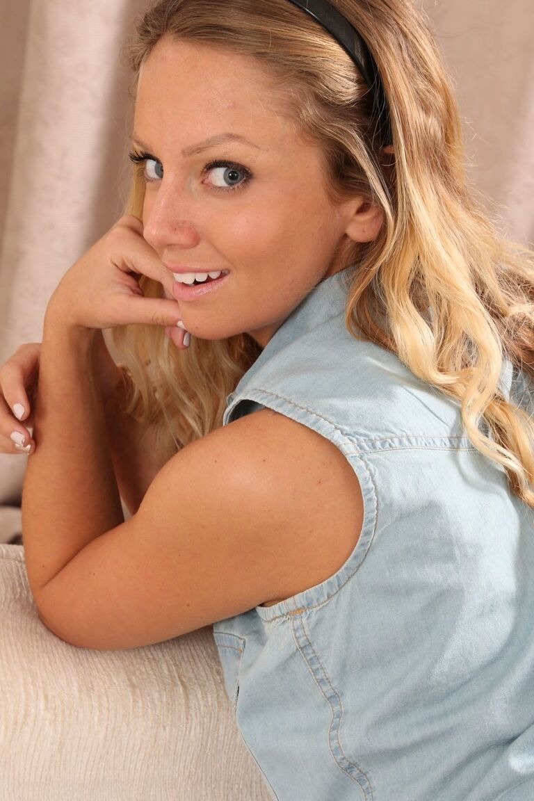 21P Suzi, une teen blonde parfaite en collants, pose sur le canapé blanc et montre ses seins