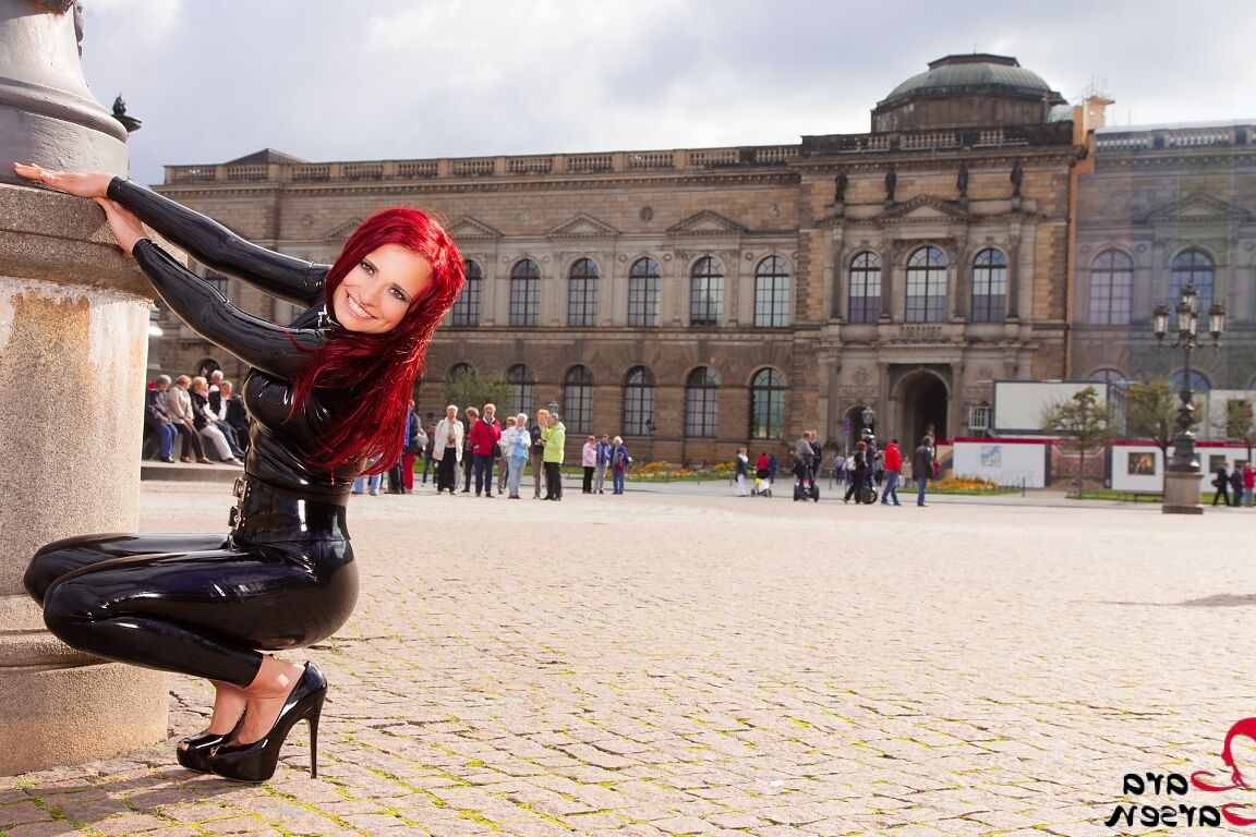 12P Solo model Lara Larsen sports red hair while modelling latex wear in a square