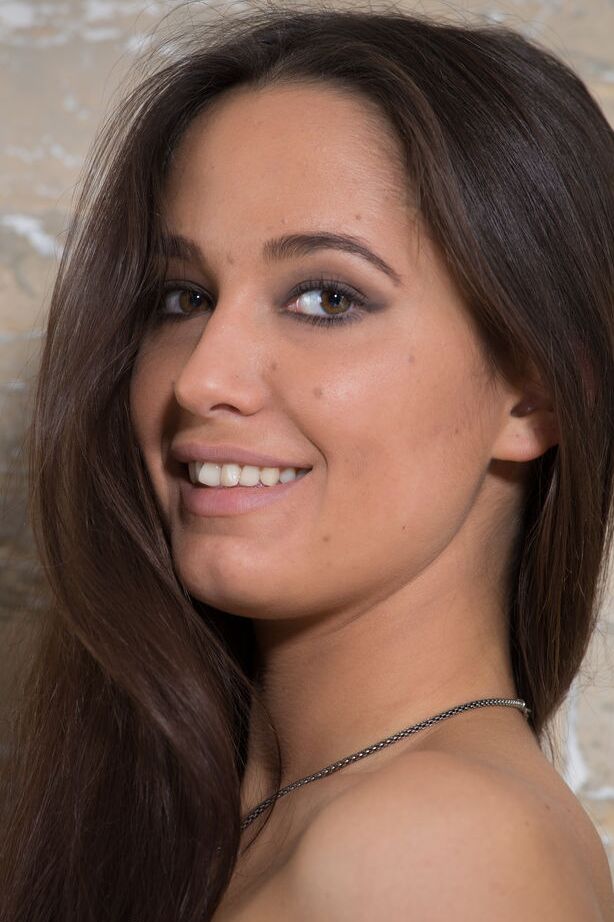 16P Amelia, mannequin adolescente, joue avec ses cheveux longs alors qu'elle est nue dans des chaussettes grises.