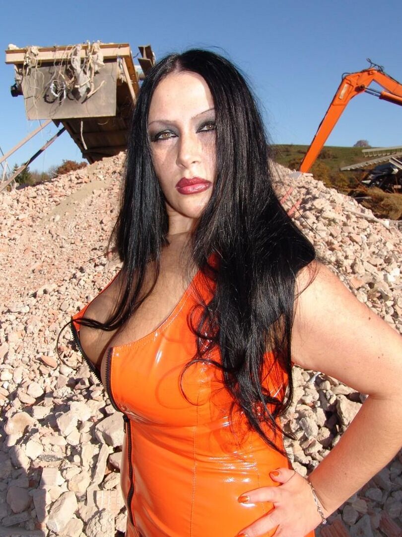 16P Mulher vestida perde seus peitos grandes com um vestido de látex perto de equipamentos pesados